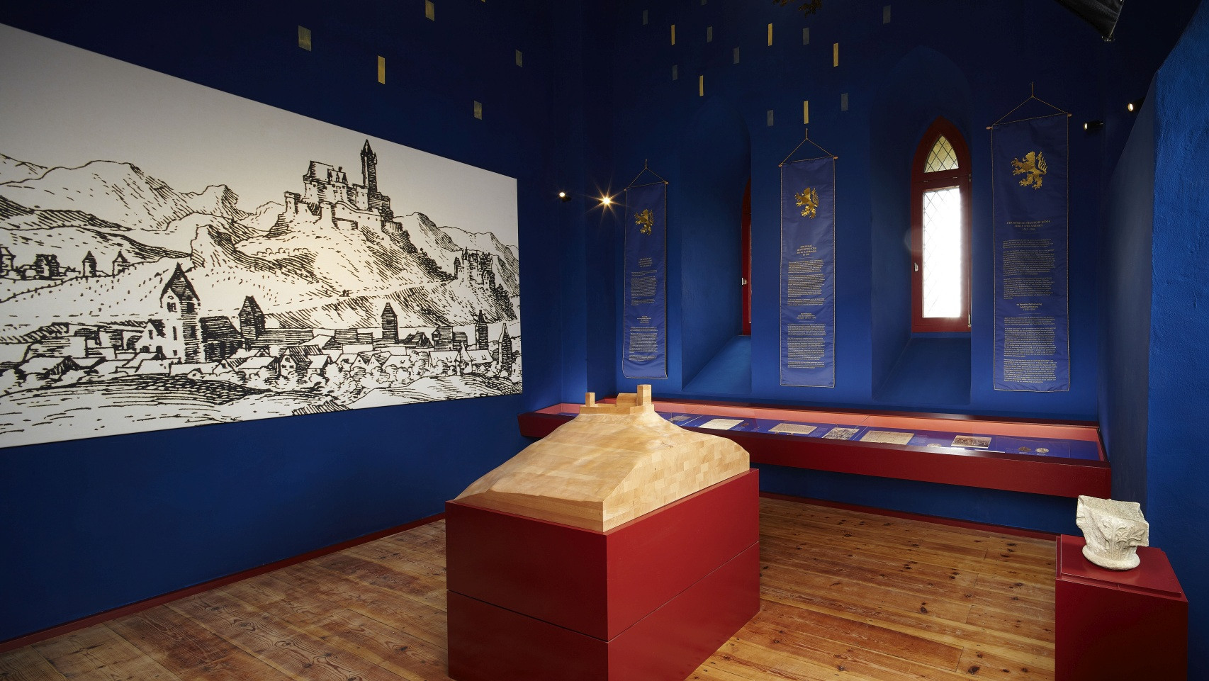 Burg Nassau - Ausstellung Blick in die Austellung mit Modell in der Mitte, Info-Bannern und einer Illustration an den Wänden